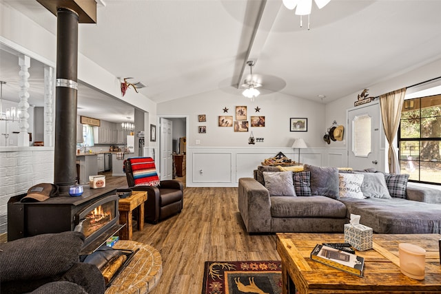 living room with a wood stove, vaulted ceiling, light wood-type flooring, and ceiling fan