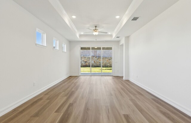 unfurnished living room featuring crown molding, a tray ceiling, light hardwood / wood-style flooring, and ceiling fan