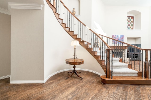 staircase with hardwood / wood-style floors and crown molding