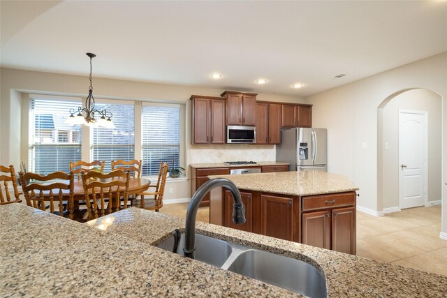 kitchen with backsplash, light stone counters, a center island, and stainless steel appliances