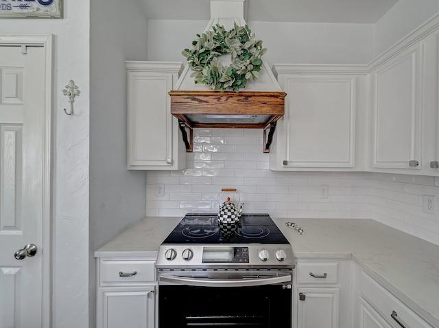 kitchen with light stone counters, white cabinets, custom exhaust hood, electric range, and decorative backsplash