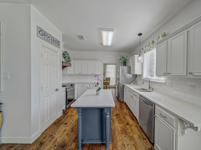 kitchen featuring a breakfast bar area, dark wood-type flooring, sink, stainless steel appliances, and hanging light fixtures