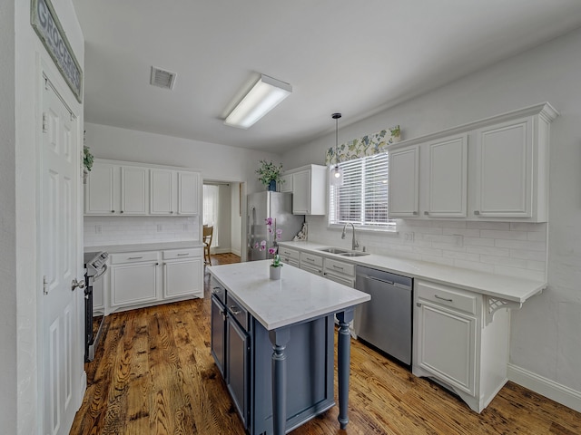 kitchen featuring hanging light fixtures, white cabinetry, hardwood / wood-style flooring, stainless steel appliances, and a breakfast bar