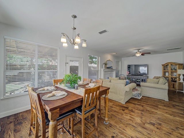 dining space with ceiling fan with notable chandelier and hardwood / wood-style flooring