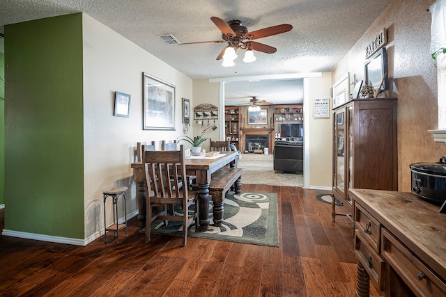 dining room with ceiling fan, dark wood-type flooring, and a textured ceiling