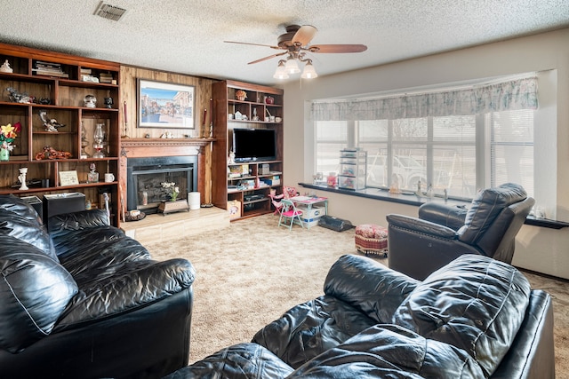 living room featuring ceiling fan, carpet flooring, and a textured ceiling