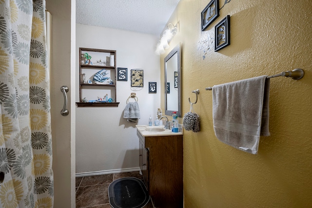 bathroom with tile patterned flooring, vanity, and a textured ceiling