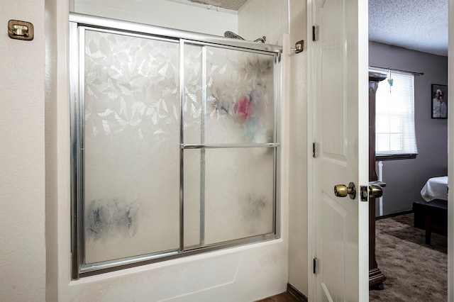 bathroom with bath / shower combo with glass door and a textured ceiling