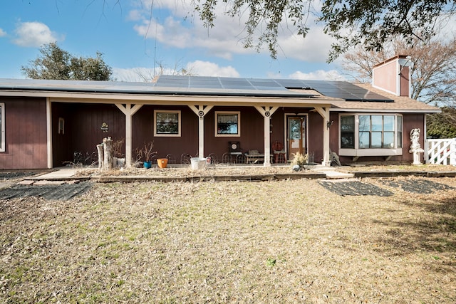 view of front facade featuring solar panels, a front lawn, and covered porch