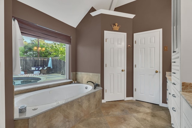 bathroom featuring vanity, lofted ceiling, and tiled bath