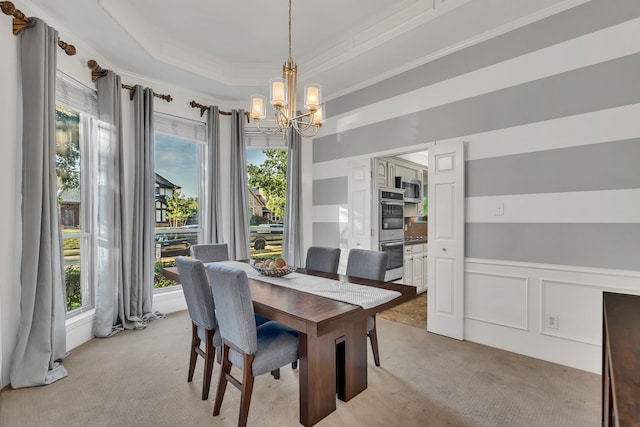 carpeted dining space featuring a raised ceiling, crown molding, and an inviting chandelier