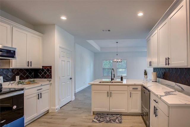 kitchen with pendant lighting, sink, kitchen peninsula, stainless steel appliances, and light hardwood / wood-style floors