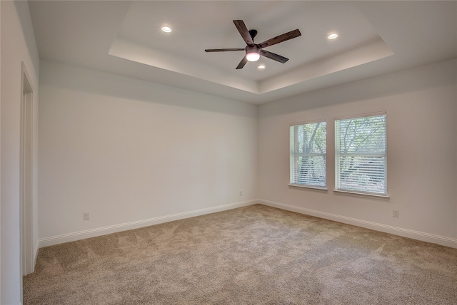 carpeted empty room featuring ceiling fan and a tray ceiling