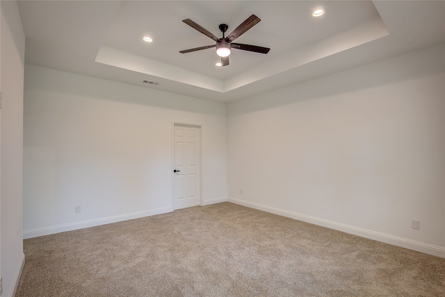 carpeted empty room with ceiling fan and a tray ceiling