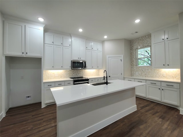 kitchen featuring a center island with sink, sink, dark wood-type flooring, and stainless steel appliances