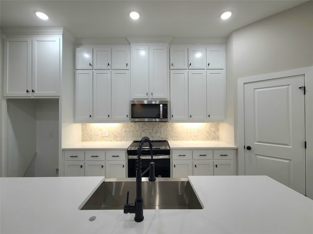 kitchen with appliances with stainless steel finishes, white cabinetry, and tasteful backsplash