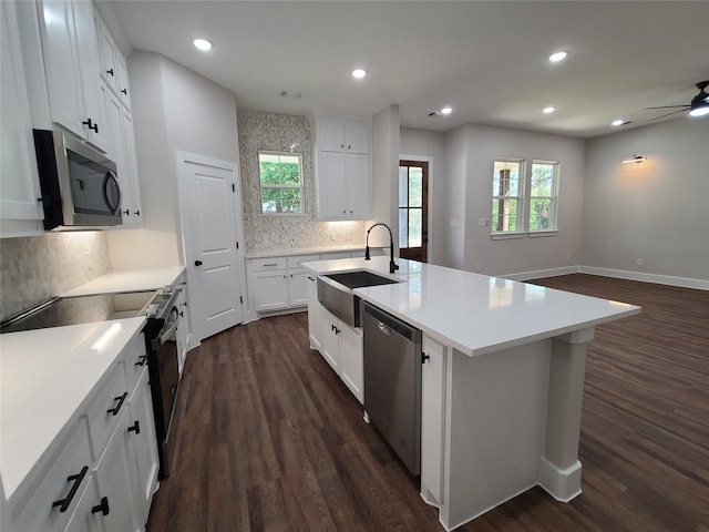 kitchen with sink, an island with sink, stainless steel appliances, and white cabinets