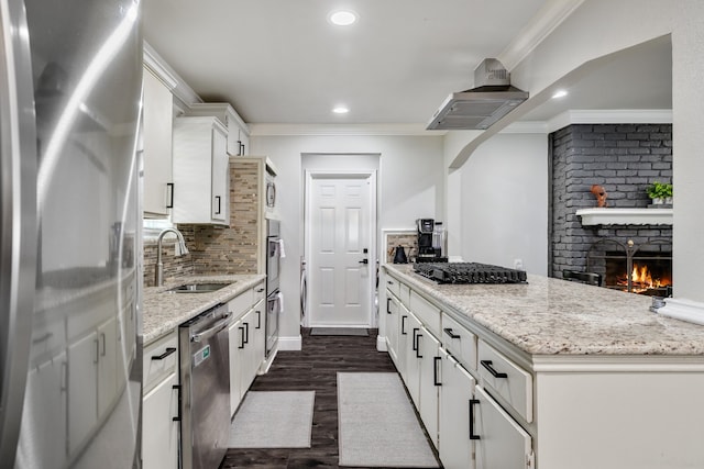 kitchen with appliances with stainless steel finishes, light stone counters, white cabinetry, and sink