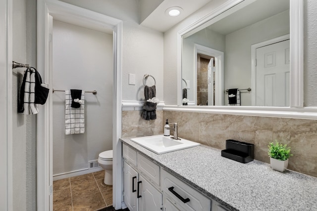 bathroom featuring toilet, tile patterned flooring, vanity, and tasteful backsplash