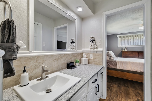 bathroom featuring tile walls, hardwood / wood-style floors, vanity, and a textured ceiling