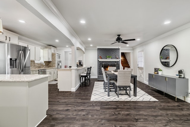 dining space featuring crown molding, ceiling fan, sink, and dark hardwood / wood-style floors