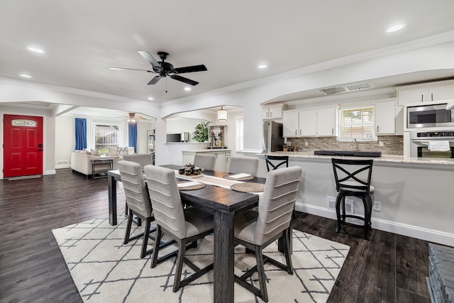 dining area featuring wood-type flooring, sink, ornamental molding, and ceiling fan