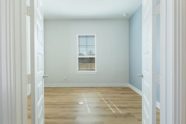 unfurnished room with light wood-style flooring and baseboards