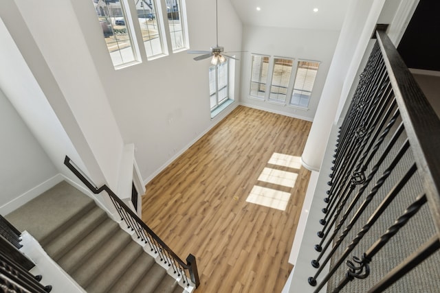 stairway featuring recessed lighting, a ceiling fan, wood finished floors, high vaulted ceiling, and baseboards