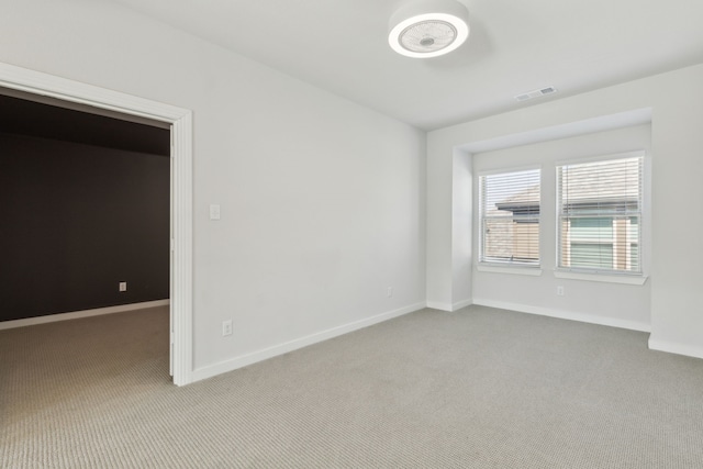 spare room with carpet floors, visible vents, and baseboards