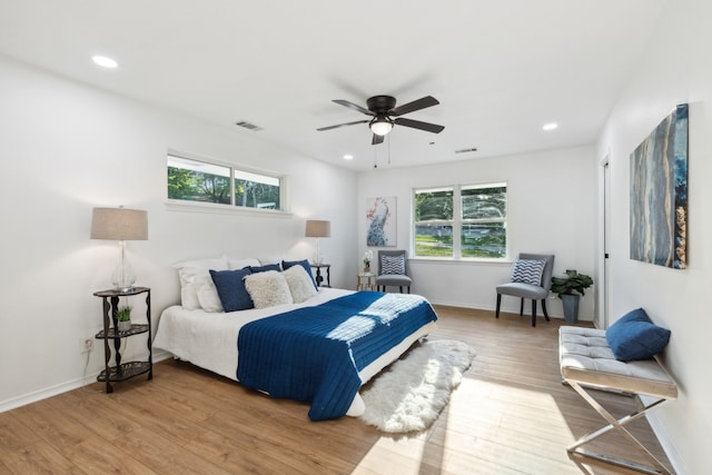 bedroom featuring ceiling fan, hardwood / wood-style floors, and multiple windows