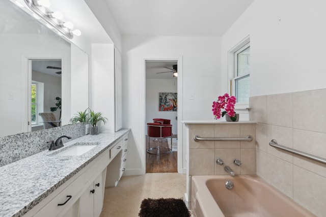 bathroom with ceiling fan, vanity, hardwood / wood-style flooring, a bathing tub, and tile walls