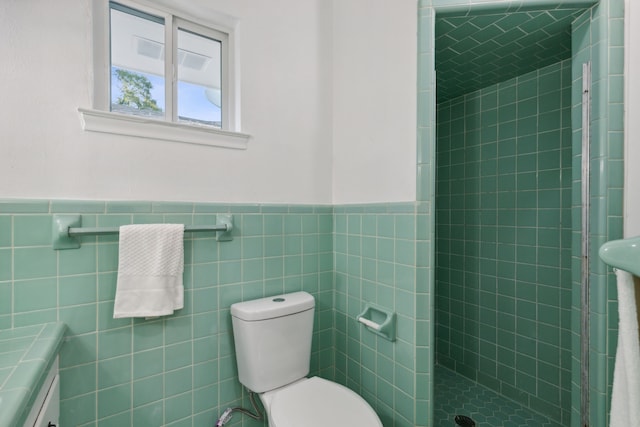 bathroom featuring a tile shower, vanity, tile walls, and toilet