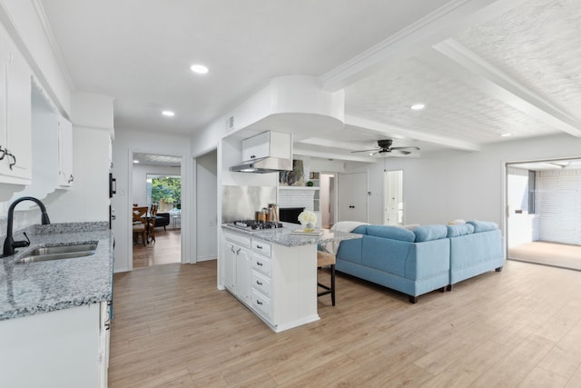 kitchen with light stone countertops, sink, light wood-type flooring, and white cabinetry