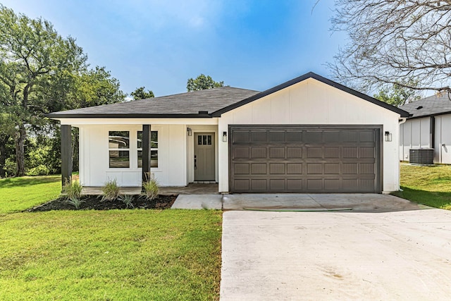 view of front facade featuring cooling unit, a garage, and a front lawn