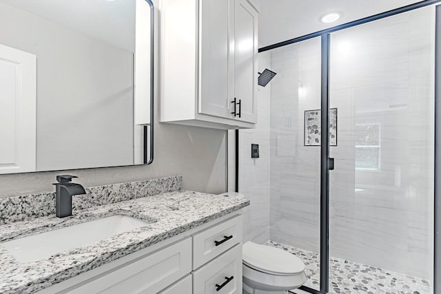 bathroom featuring an enclosed shower, vanity, and toilet