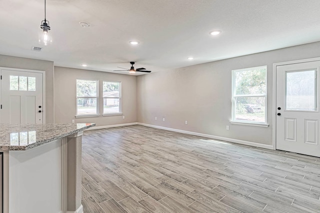 unfurnished living room featuring plenty of natural light, light hardwood / wood-style flooring, and ceiling fan