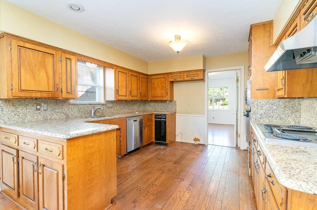 kitchen with light hardwood / wood-style floors, decorative backsplash, extractor fan, and appliances with stainless steel finishes