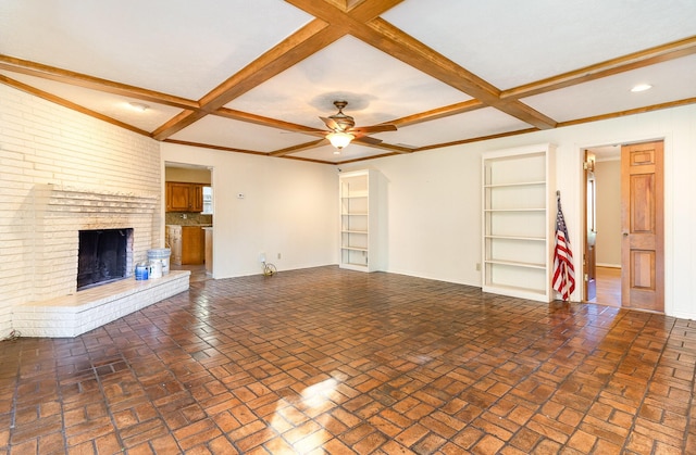 unfurnished living room with beam ceiling, built in features, coffered ceiling, and a brick fireplace