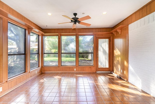 unfurnished sunroom featuring ceiling fan and a healthy amount of sunlight