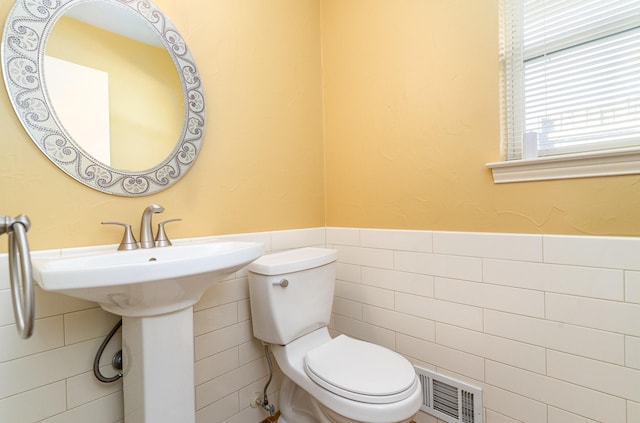 bathroom featuring toilet and tile walls