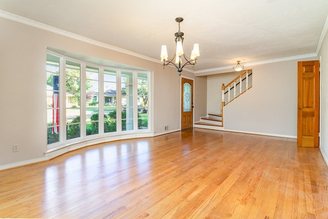 spare room with a healthy amount of sunlight, light wood-type flooring, crown molding, and an inviting chandelier