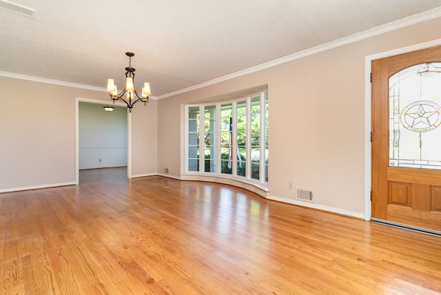 entrance foyer featuring light hardwood / wood-style floors, ornamental molding, and a chandelier