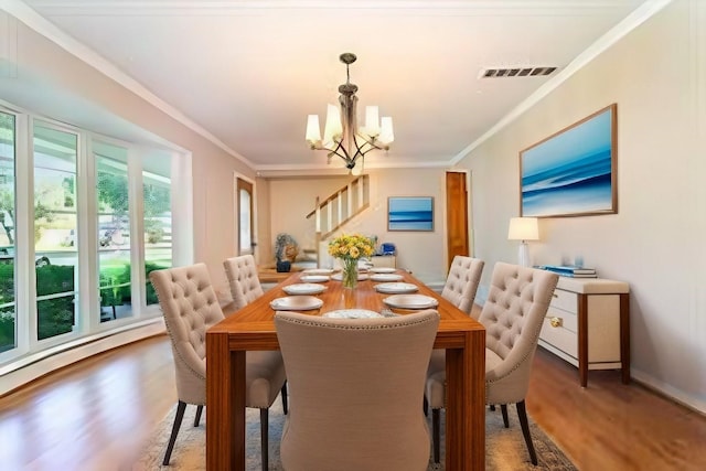 dining space with wood-type flooring, a chandelier, and ornamental molding