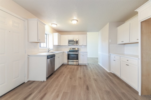 kitchen featuring a textured ceiling, white cabinetry, stainless steel appliances, and light hardwood / wood-style flooring