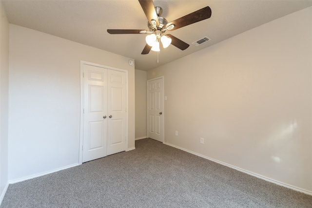 unfurnished bedroom featuring ceiling fan, a closet, and carpet flooring