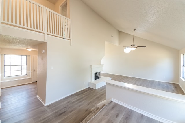 stairs featuring ceiling fan, high vaulted ceiling, hardwood / wood-style flooring, and a textured ceiling