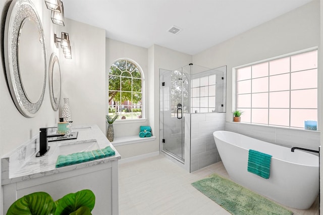 full bathroom featuring double vanity, visible vents, a soaking tub, a shower stall, and tile walls