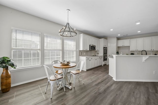 dining space featuring dark hardwood / wood-style flooring, sink, and a notable chandelier