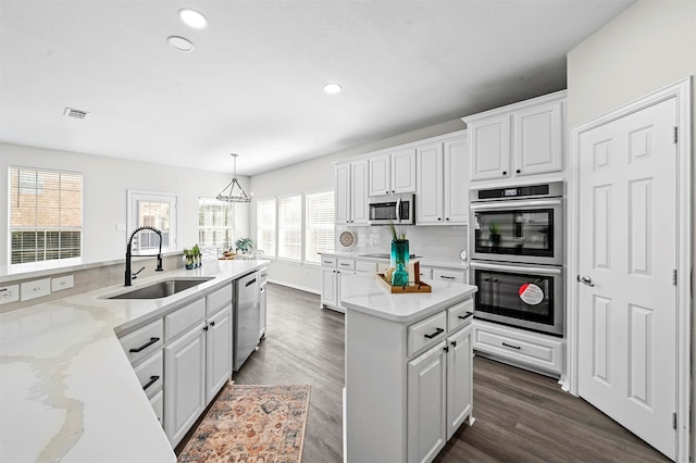 kitchen featuring white cabinets, stainless steel appliances, sink, and decorative light fixtures