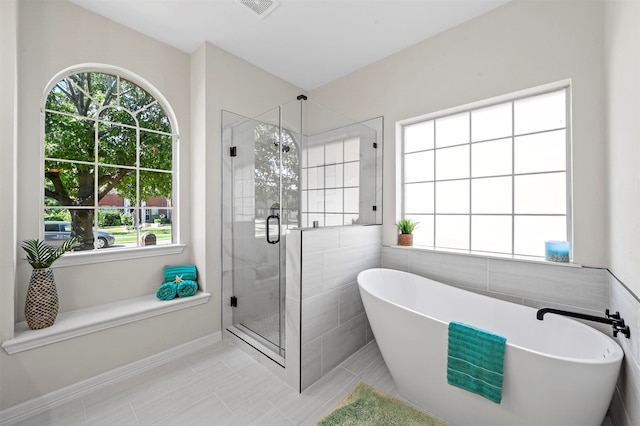 bathroom with tile patterned flooring and separate shower and tub